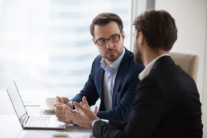 Two young businessmen discuss or plan project in office